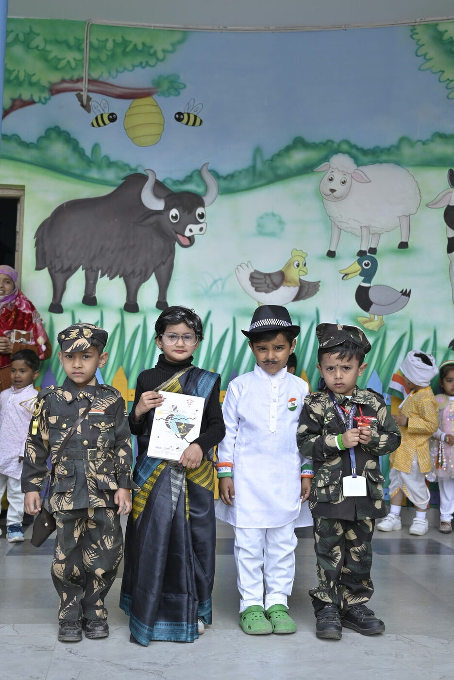 Little ones in fancy dress as soldiers and national leaders against the school's painted mural