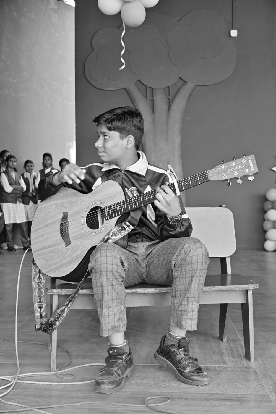 A student plays the guitar on stage during the Children's Day programme