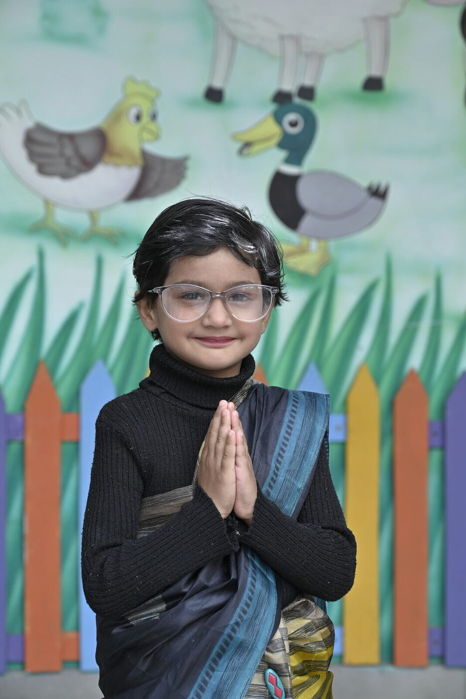 A kindergarten student in costume greets with a namaste at the fancy dress event