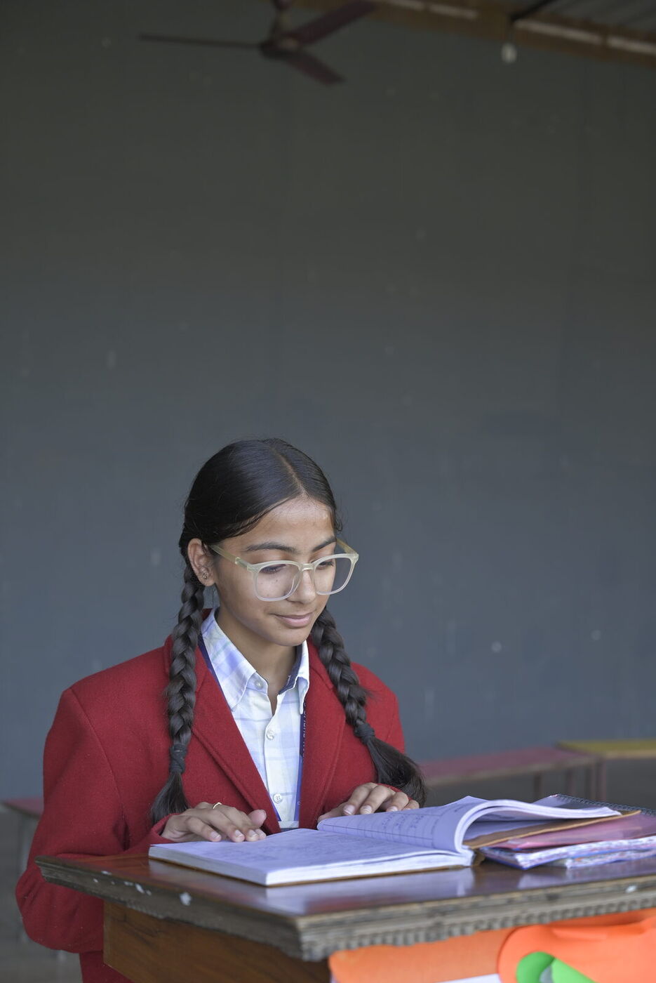 A student reads her textbook at her desk in class