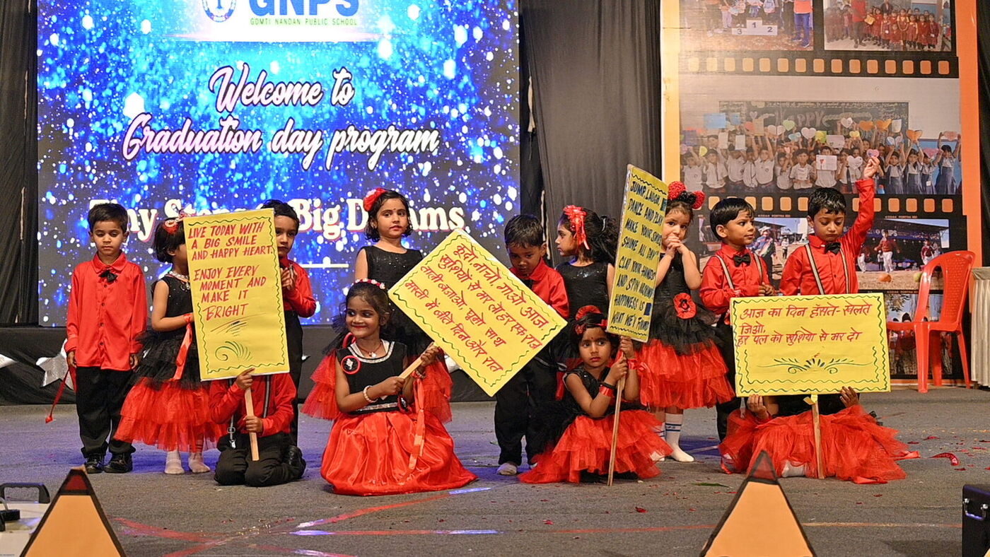 Kindergarten children hold handmade placards during a stage presentation at Graduation Day 2026