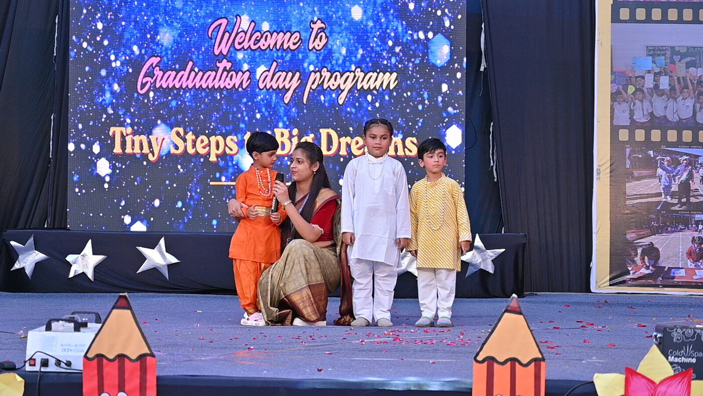 Young performers with their teacher under the "Tiny Steps to Big Dreams" banner