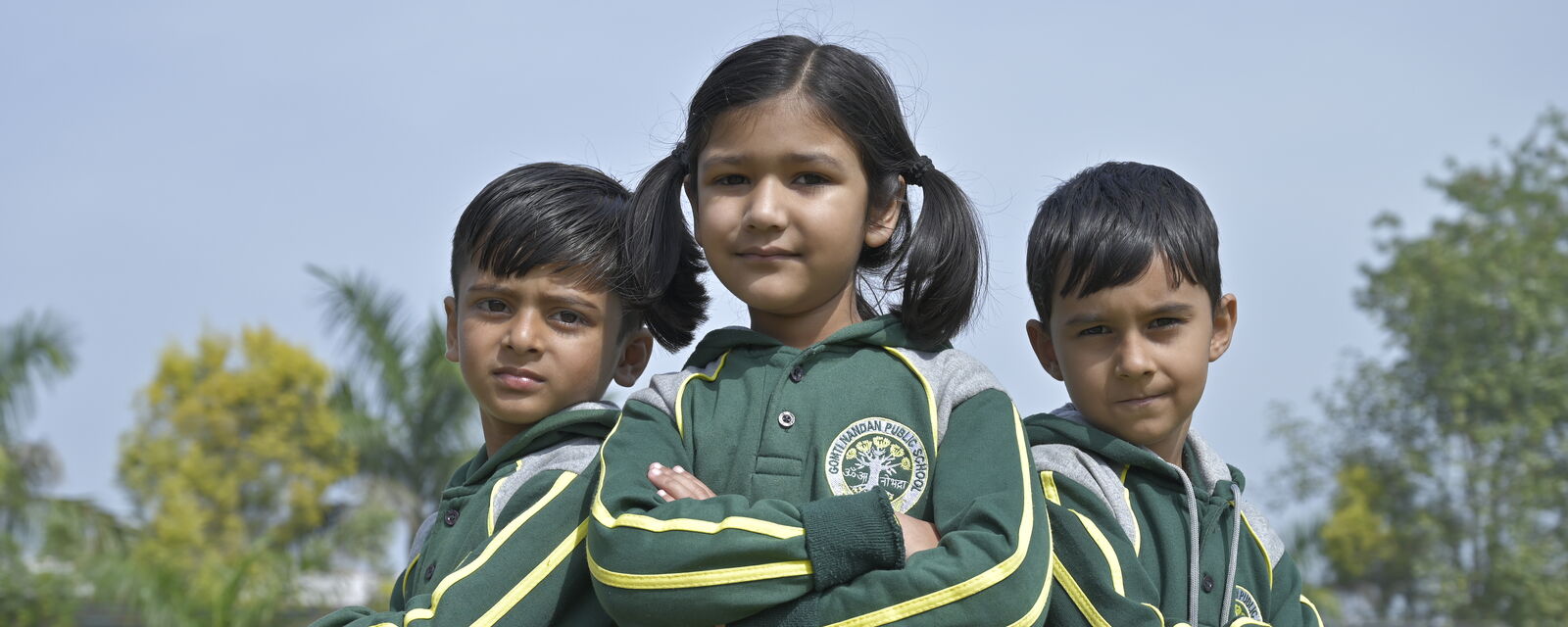 Three young GNPS students in winter uniform on the school lawn