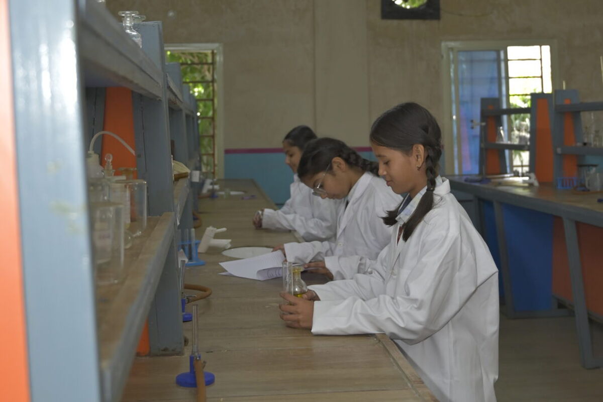 Students in lab coats doing a practical in the chemistry lab