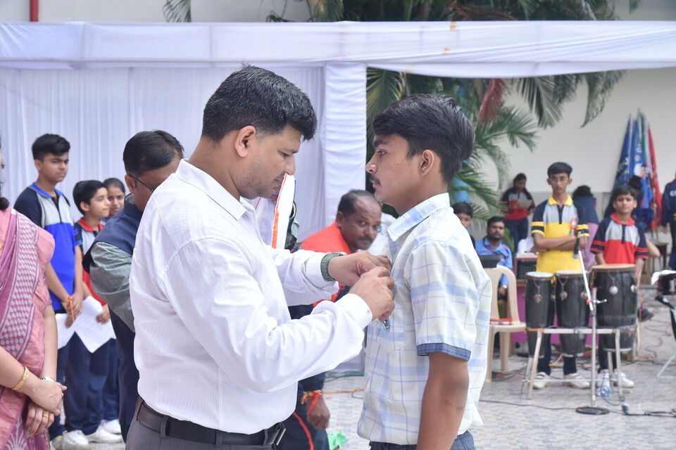 A teacher pins a badge on a student council member
